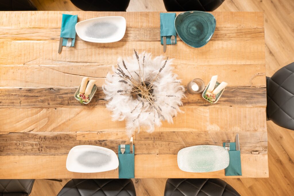 Gedeckter Holztisch mit modernen Dekoelementen und schönen Tellern