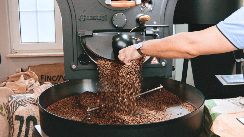 Ein Mann gießt Kaffeebohnen in eine Kaffeemühle